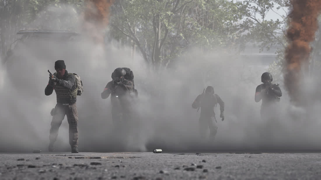 Soldaten rücken als Silhouetten durch dichten Staub vor.